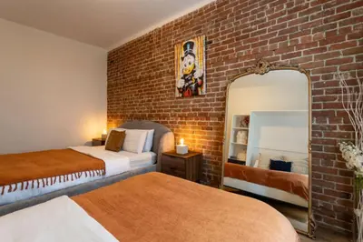 a bedroom with two beds and a brick wall at Sleek 2BR in Heart of Downtown Montreal in Montréal