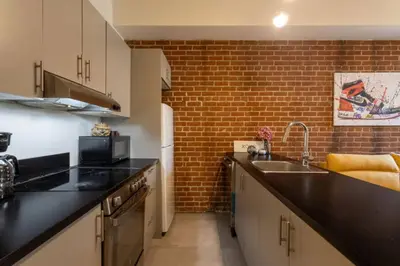 a kitchen with a sink and a brick wall at Sleek 2BR in Heart of Downtown Montreal in Montréal