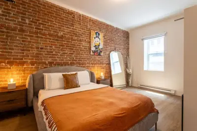 a bedroom with a brick wall and a bed at Sleek 2BR in Heart of Downtown Montreal in Montréal