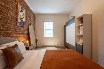 a bedroom with a bed and a brick wall at Sleek 2BR in Heart of Downtown Montreal in Montréal
