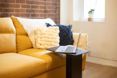 a laptop sitting on a table on a couch at Sleek 2BR in Heart of Downtown Montreal in Montréal