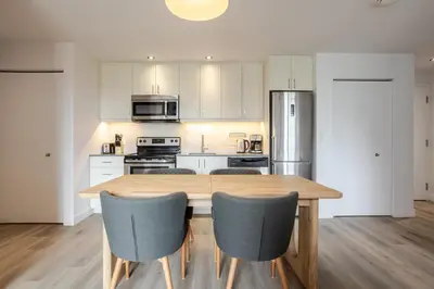 a kitchen with a wooden table and chairs at Modern Heritage Stay Upscale 2BR in Old Port in Montréal