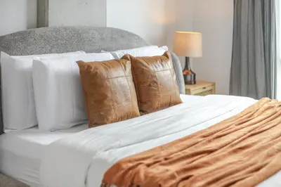 a white bed with white sheets and brown pillows at Modern Heritage Stay Upscale 2BR in Old Port in Montréal