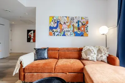 a living room with a brown couch and a painting at Modern Heritage Stay Upscale 2BR in Old Port in Montréal