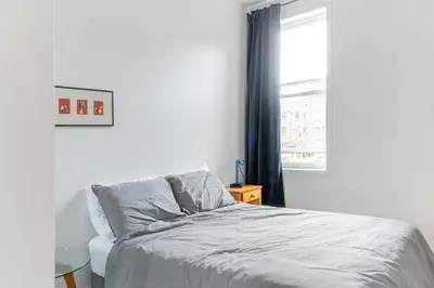 a white bedroom with a bed and a window at Appart lumineux et chaleureux in Montréal