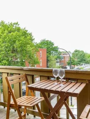 a wooden table and two wine glasses on a balcony at Appart lumineux et chaleureux in Montréal