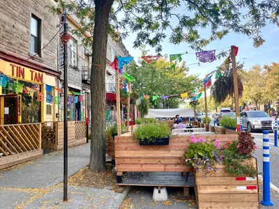 a wooden bench on a city street with flowers at MTLVacationRentals - The City Chalet in Montréal