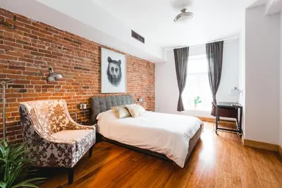 a bedroom with a brick wall and a bed and a chair at MTLVacationRentals - The City Chalet in Montréal