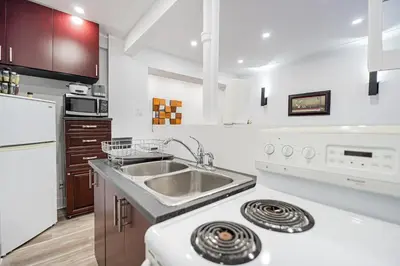 a white kitchen with a sink and a stove at Confort Suprême Grand Appartement 3 Chambres Design in Montréal