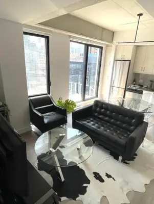 a living room with a black couch and a glass table at Loft moderne au coeur de Montreal in Montréal
