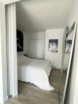a bedroom with a white bed and a mirror at Loft moderne au coeur de Montreal in Montréal