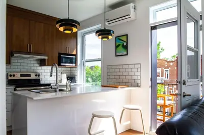 a kitchen with a counter and two stools at Appartement cozy et lumineux avec parking in Montréal