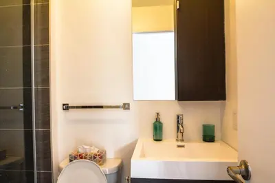 a bathroom with a sink and a toilet and a mirror at Appartement cozy et lumineux avec parking in Montréal