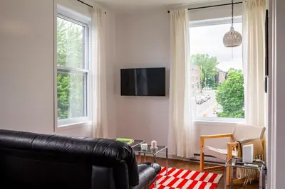 a living room with a black leather couch and a window at Appartement cozy et lumineux avec parking in Montréal
