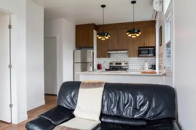 a living room with a leather couch in a kitchen at Appartement cozy et lumineux avec parking in Montréal