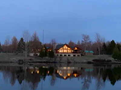 a house sitting next to a lake at night at Impérial du Domaine de la Chasse Gardée in Linière