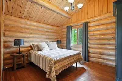 a bedroom with a bed in a log cabin at Impérial du Domaine de la Chasse Gardée in Linière