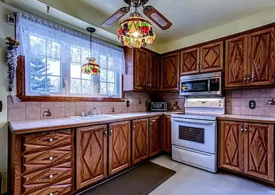 a kitchen with wooden cabinets and a chandelier at Private roomC Fee parking 15min downtown in Longueuil