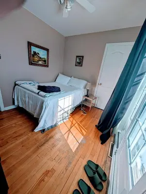 a bedroom with a bed and a wooden floor at Private roomC Fee parking 15min downtown in Longueuil