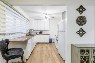 a kitchen with white cabinets and a black chair at Stylish 6-BR House close to DT with free parking in Brossard