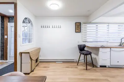 a kitchen with a counter and a chair in a room at Stylish 6-BR House close to DT with free parking in Brossard