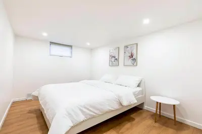 a white bedroom with a bed and a table at Stylish 6-BR House close to DT with free parking in Brossard