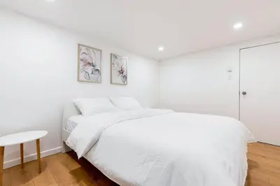 a white bedroom with a bed and a table at Stylish 6-BR House close to DT with free parking in Brossard