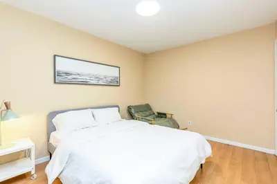 a bedroom with a white bed and a chair at Stylish 6-BR House close to DT with free parking in Brossard