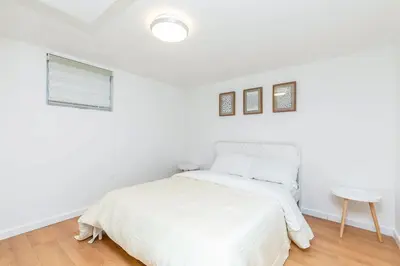 a white bedroom with a bed and a table at Stylish 6-BR House close to DT with free parking in Brossard