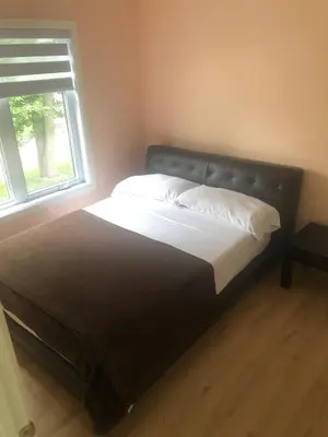 a large bed in a bedroom with a window at Peaceful oasis near airport private entrance in Pointe-Claire