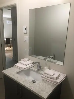 a bathroom with a sink with a mirror and towels at Peaceful oasis near airport private entrance in Pointe-Claire