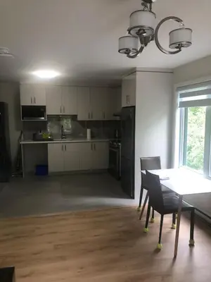 a kitchen with white cabinets and a table with chairs at Peaceful oasis near airport private entrance in Pointe-Claire