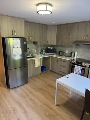 a kitchen with a refrigerator and a table in it at All inclusive pied à terre near airport 2nd bed extra twenty dollars cash in Pointe-Claire
