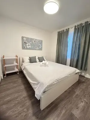 a bedroom with a large bed with white sheets at 2 bedroom, subway, free parking. in Longueuil