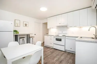 a white kitchen with white appliances and a table at 2 bedroom, subway, free parking. in Longueuil