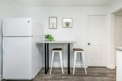 a kitchen with a table with stools and a refrigerator at 2 bedroom, subway, free parking. in Longueuil