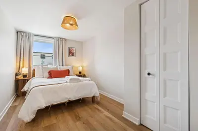 a white bedroom with a bed and a window at Escapade Chambly in Chambly