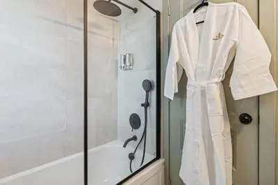 a white robe hanging in a shower in a bathroom at Escapade Chambly in Chambly