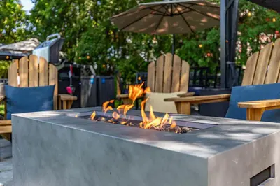 a fire pit on a table with chairs and an umbrella at Escapade Chambly in Chambly