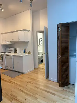 a kitchen with white cabinets and a wooden floor at La Galerie Privée Luxe & Impeccable Stay in Montréal