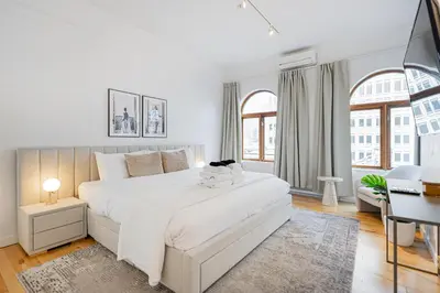 a white bedroom with a large white bed and a desk at La Galerie Privée Luxe & Impeccable Stay in Montréal
