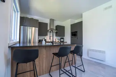 a kitchen with three bar stools and a counter at Spa & Adventure - Chalet Valikas in Weedon-Centre