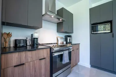 a kitchen with wooden cabinets and a stove top oven at Spa & Adventure - Chalet Valikas in Weedon-Centre