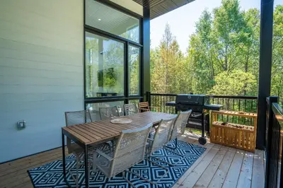 a screened porch with a table and chairs and a grill at Spa & Adventure - Chalet Valikas in Weedon-Centre