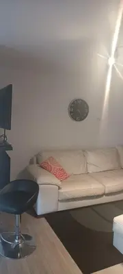 a white couch in a room with a clock on the wall at Résidence le HAvre in Laval