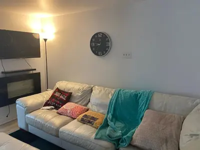 a living room with a couch with pillows and a clock at Résidence le HAvre in Laval