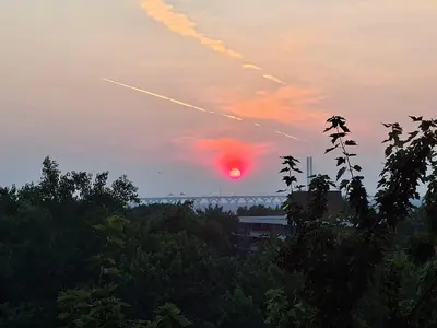 a sunset with a plane trail in the sky at Nun island in Montréal