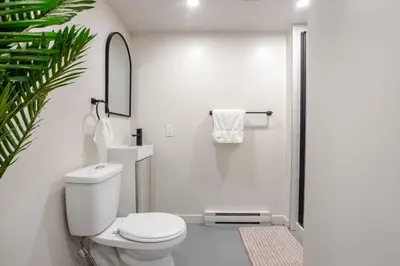 a white bathroom with a toilet and a shower at Plateau Powerhouse 5BR and 2BA Apt in Montréal