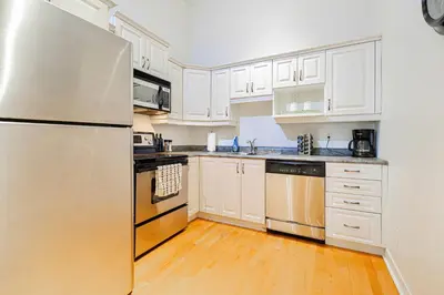 a kitchen with white cabinets and a stainless steel refrigerator at Suite La Madame - Designer Downtown Nest in Montréal