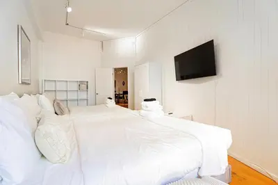 a white bedroom with a large bed and a flat screen tv at Suite La Madame - Designer Downtown Nest in Montréal